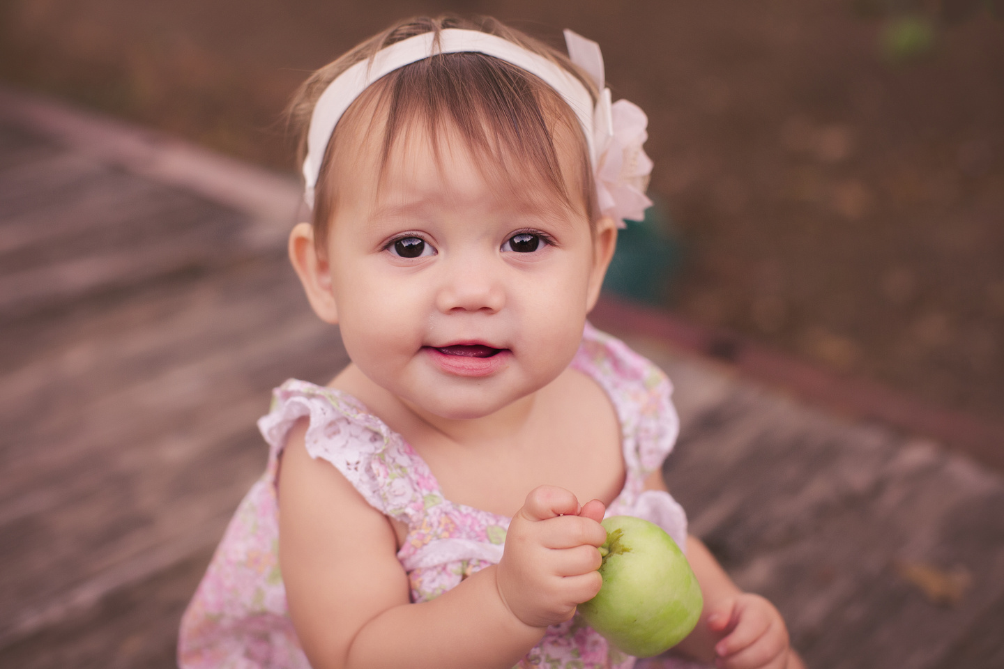 baby sitting up for photography session holding a fruit