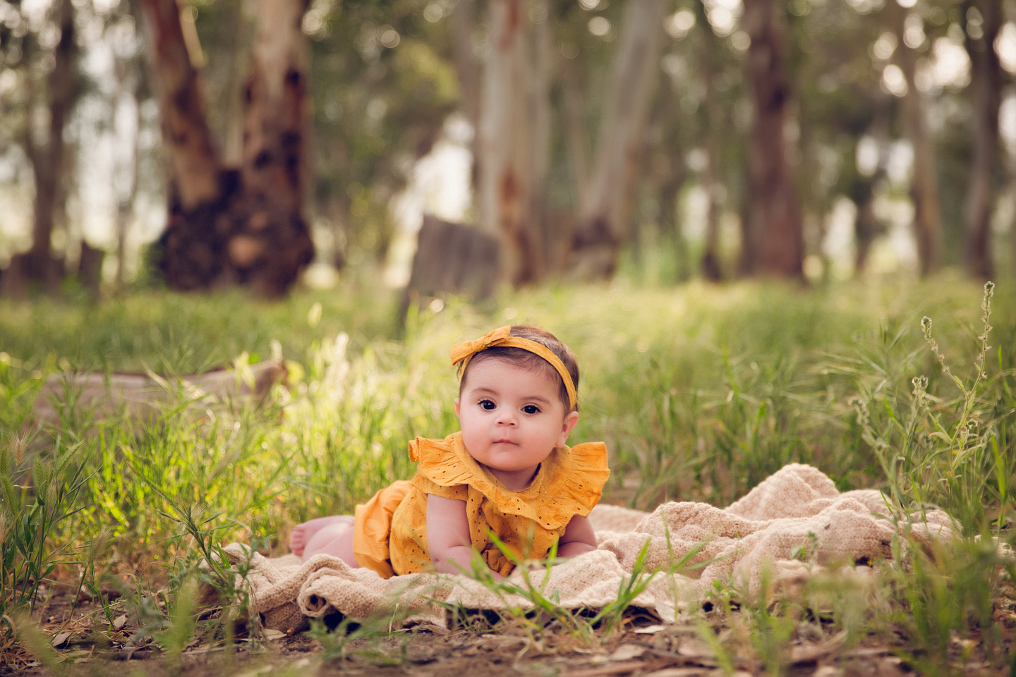young baby laying on the ground photography