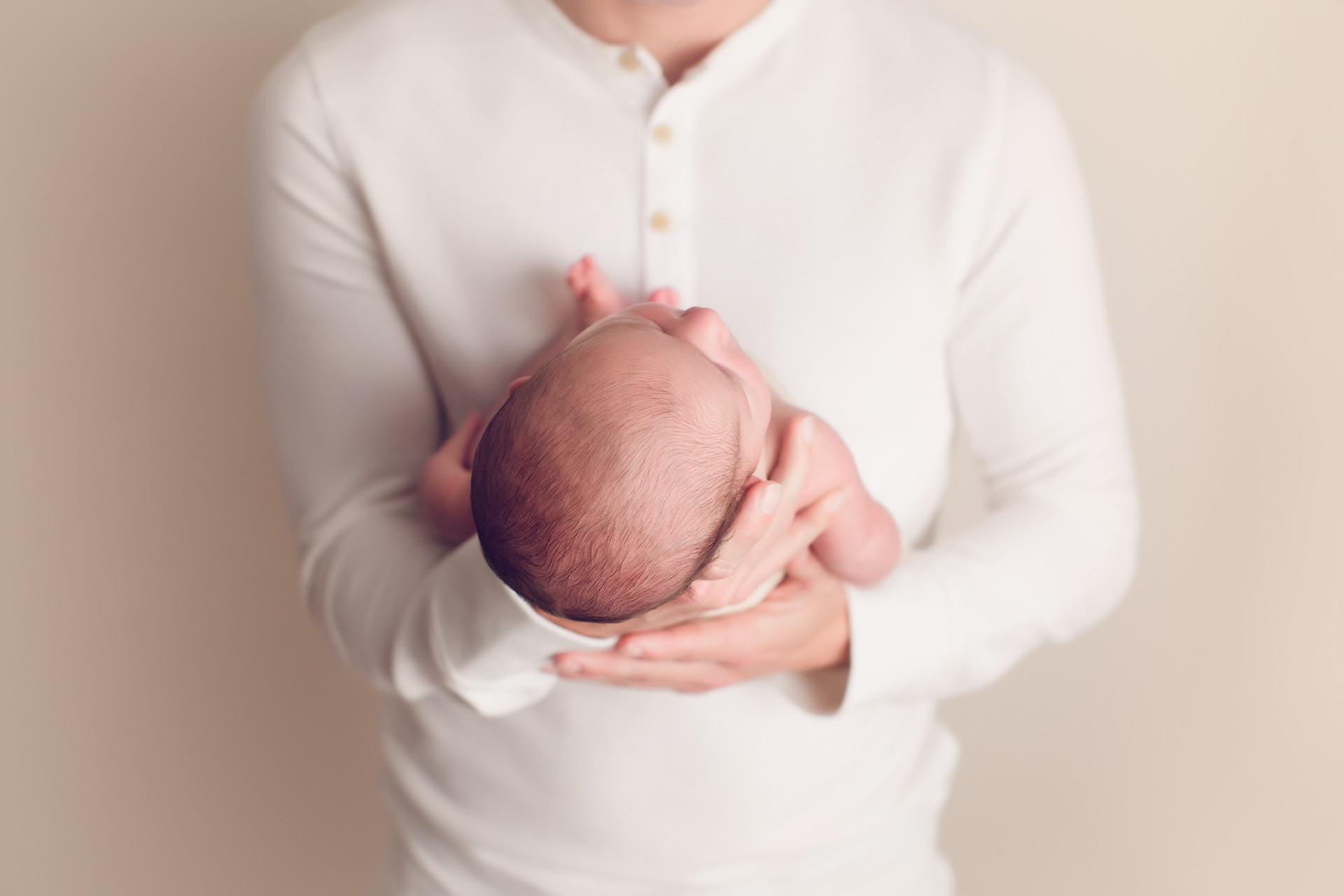 Dad in white shirt holding a newborn baby in his hands